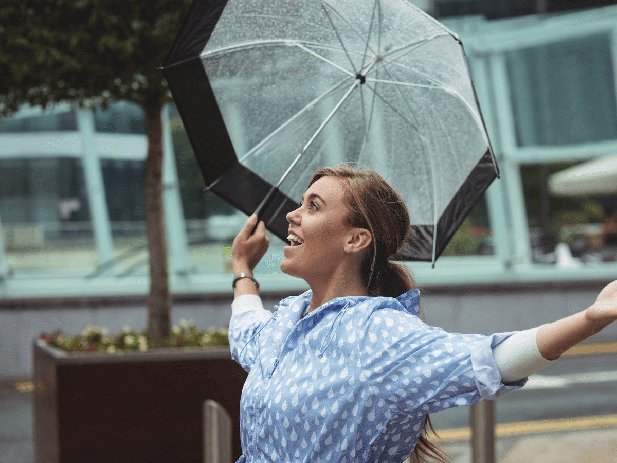 A woman celebrating holding an umbrella smiling, as she's managing her business risk with the help of Lily Head Finance